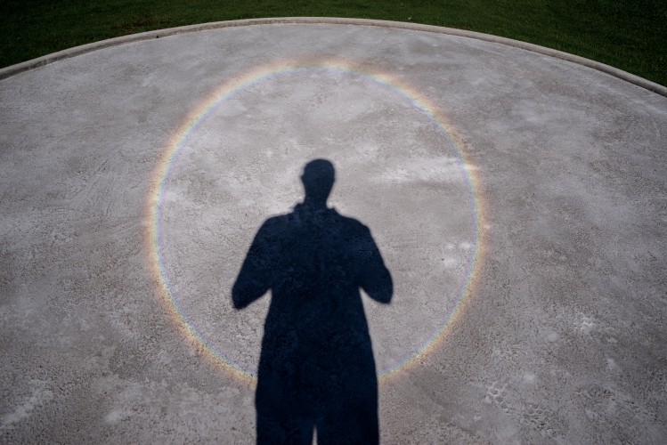 A shadow of a man looking at a circle of cement